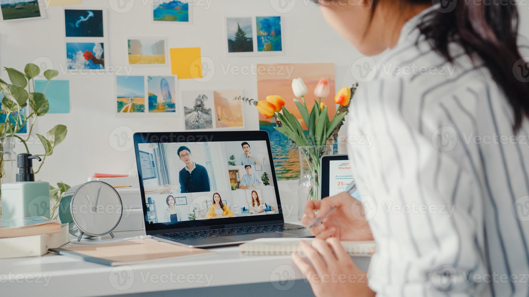 joven empleada de asia escucha al líder en la videollamada con diversos colegas multirraciales en línea con la computadora portátil en casa. la educación a distancia. alumna aprende en línea en casa, concepto de reunión en línea. foto