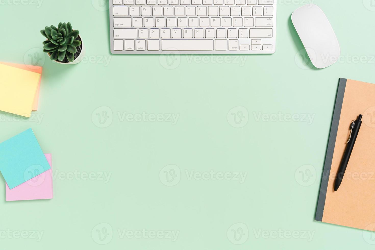 espacio de trabajo mínimo: foto creativa plana del escritorio del espacio de trabajo. escritorio de oficina de vista superior con teclado, mouse y libro sobre fondo de color verde pastel. vista superior con espacio de copia, fotografía plana.