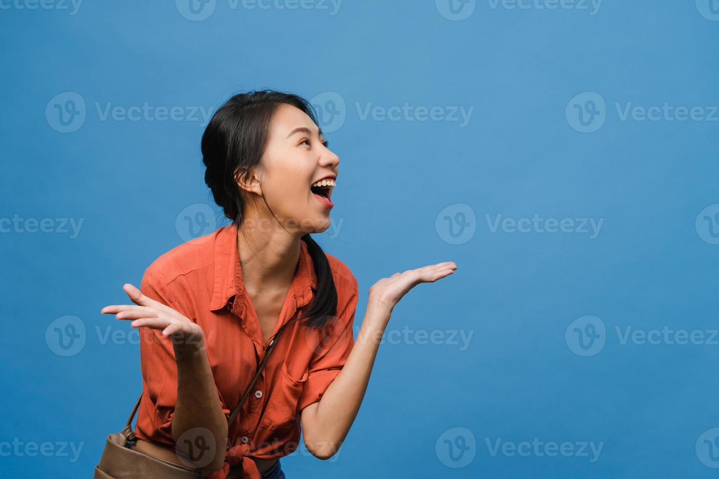 Young Asia lady feel happiness with positive expression, joyful surprise funky, dressed in casual cloth isolated on blue background. Happy adorable glad woman rejoices success. Facial expression. photo