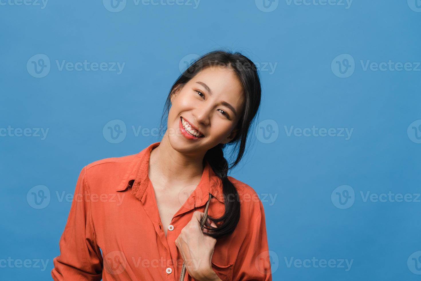 joven asiática con expresión positiva, sonrisa amplia, vestida con ropa informal y mirando a cámara sobre fondo azul. feliz adorable mujer alegre se regocija con el éxito. concepto de expresión facial. foto