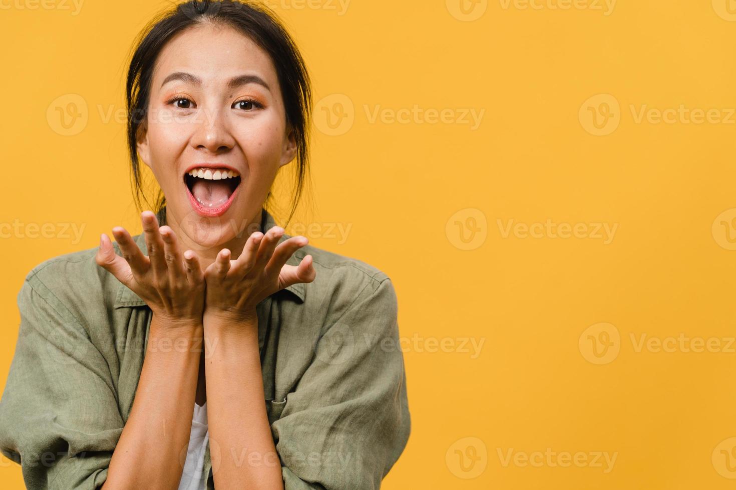 La joven asiática siente felicidad con expresión positiva, alegre sorpresa funky, vestida con ropa informal y mirando a cámara aislada sobre fondo amarillo. feliz adorable mujer alegre se regocija con el éxito. foto