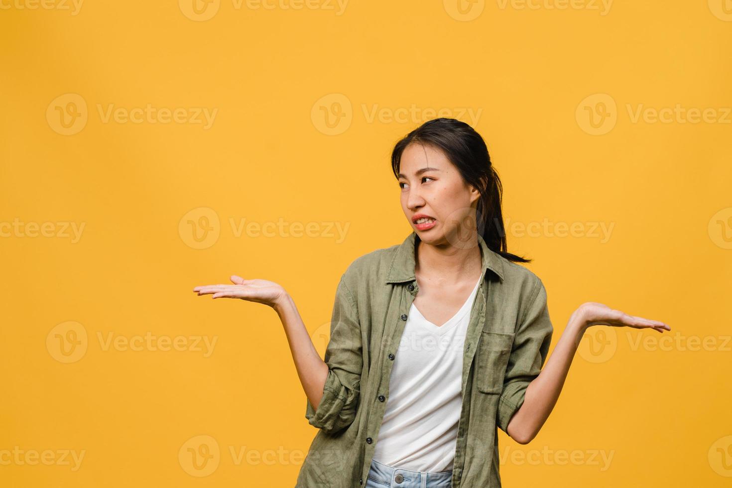 Retrato de joven asiática con expresión negativa, gritos emocionados, llorando emocionalmente enojado en ropa casual aislado sobre fondo amarillo con espacio de copia en blanco. concepto de expresión facial. foto