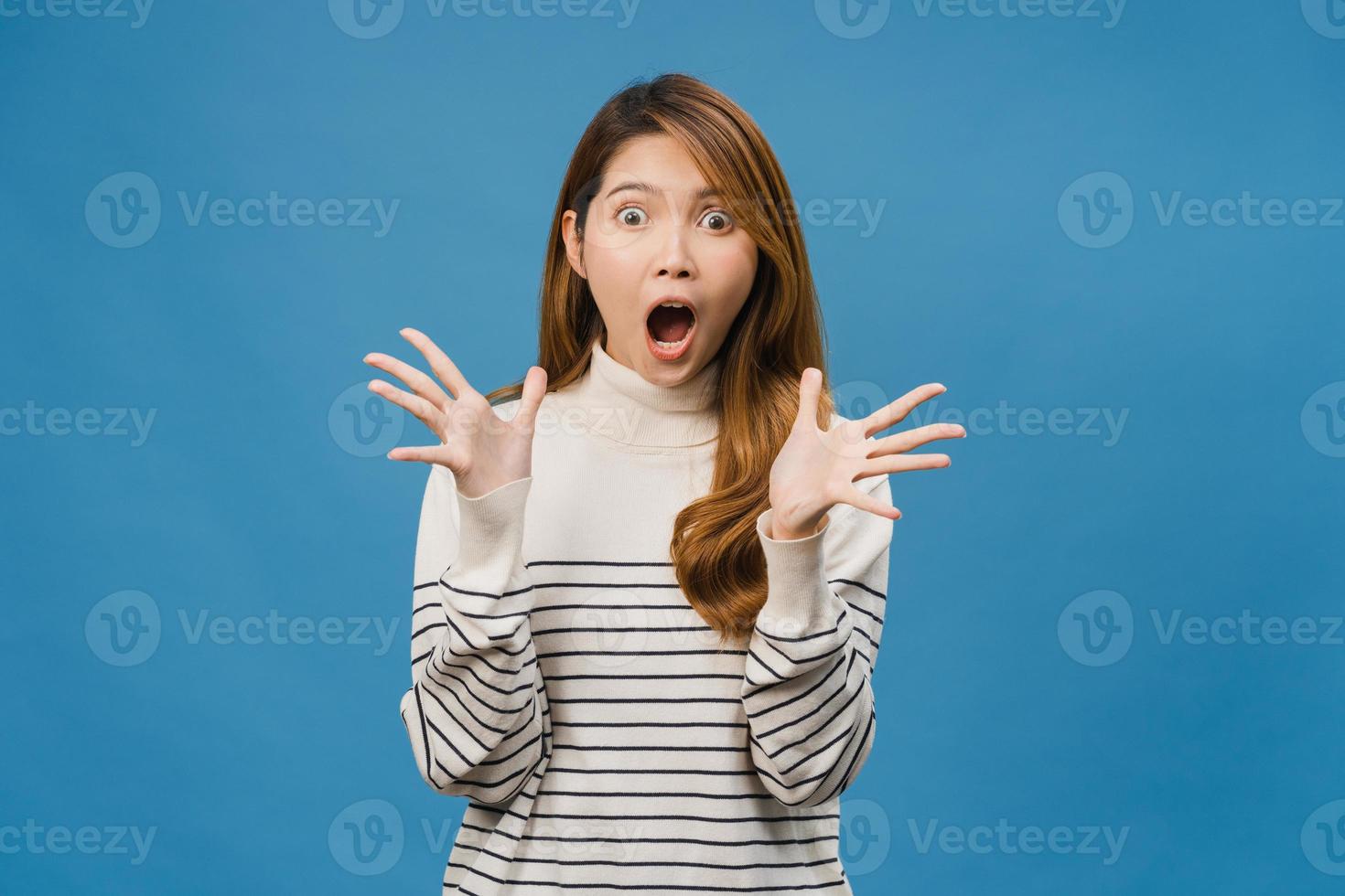 Joven asiática sintiendo felicidad con expresión positiva, alegre sorpresa funky, vestida con ropa casual y mirando a cámara aislada sobre fondo azul. feliz adorable mujer alegre se regocija el éxito foto