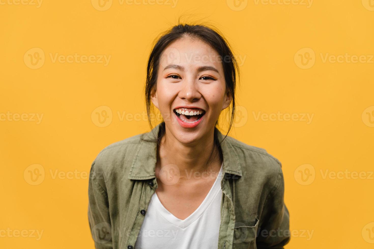 Jovencita asiática con expresión positiva, sonrisa amplia, vestida con ropa casual y mirando a cámara sobre fondo amarillo. feliz adorable mujer alegre se regocija con el éxito. concepto de expresión facial. foto