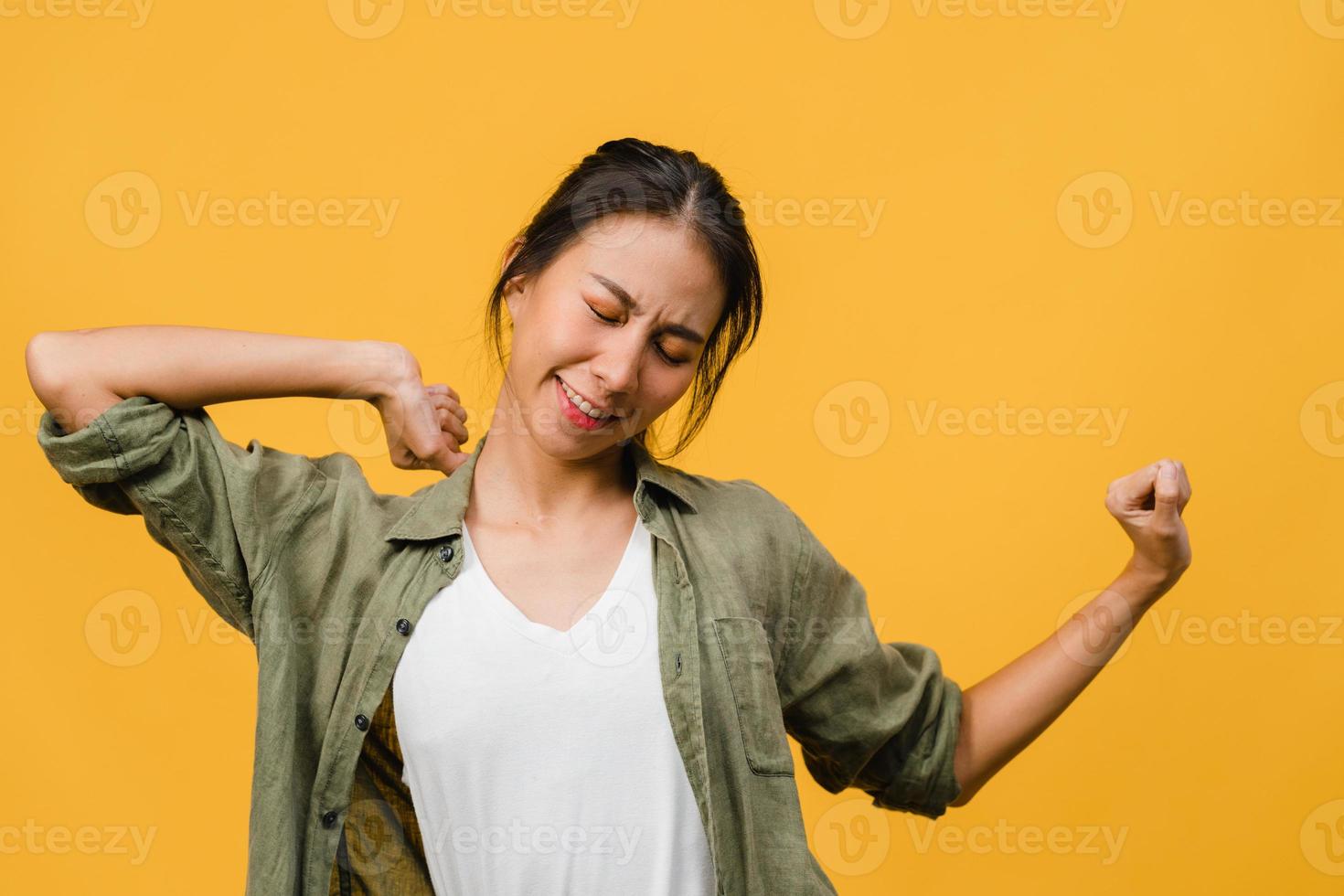 jovencita de asia con expresión positiva, alegre y emocionante, vestida con ropa casual sobre fondo amarillo con espacio vacío. feliz adorable mujer alegre se regocija con el éxito. concepto de expresión facial. foto