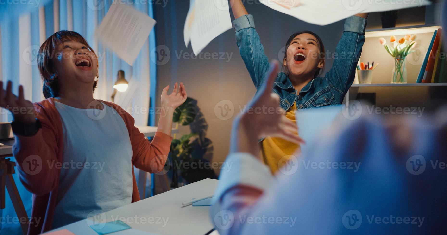 Multiracial group young asia creative people in smart casual wear discussing business gesture hand high five, laugh and smile together in brainstorm meeting at night office. Coworker teamwork concept. photo