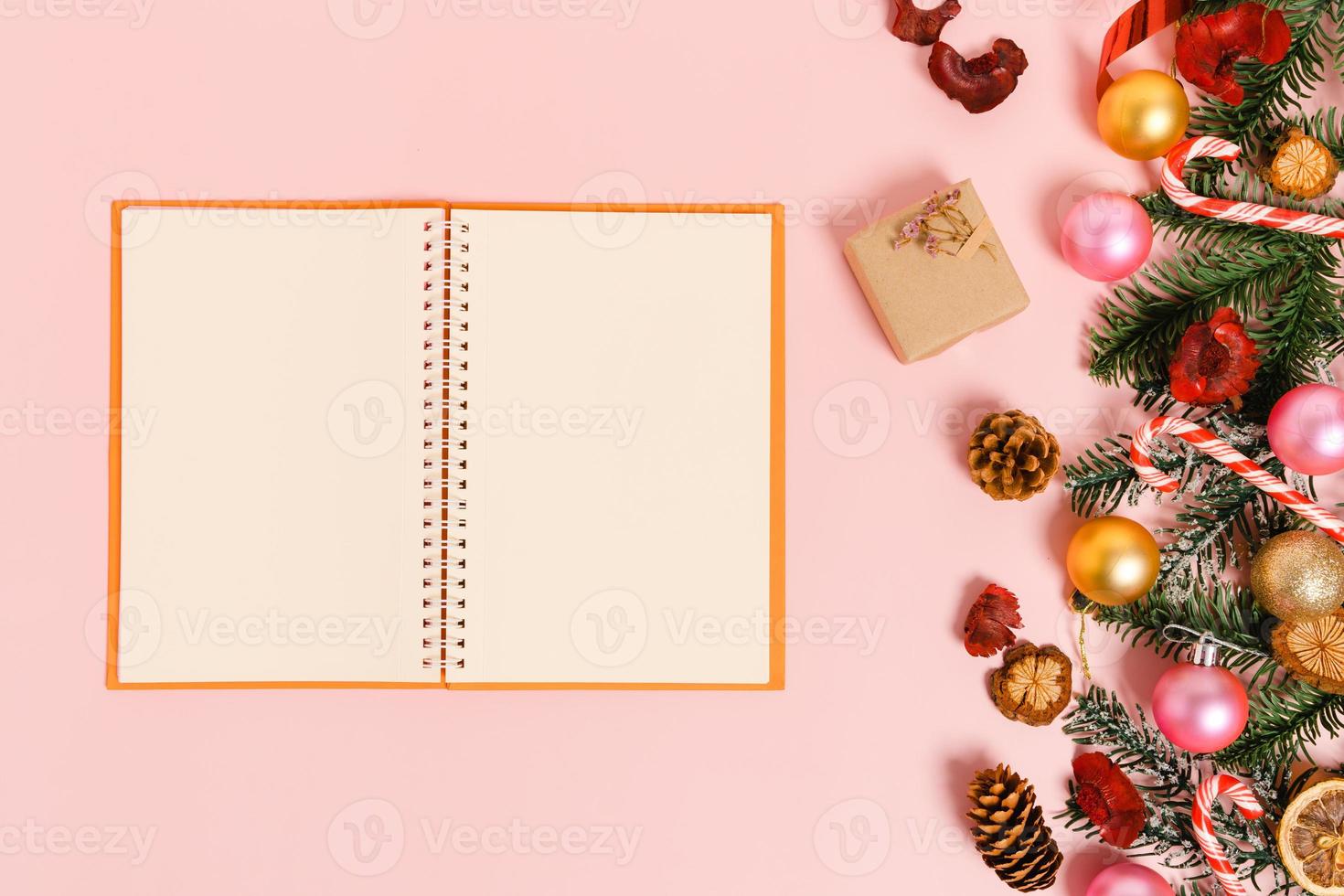 Minimal creative flat lay of winter christmas traditional composition and new year holiday season. Top view open mockup black notebook for text on pink background. Mock up and copy space photography. photo