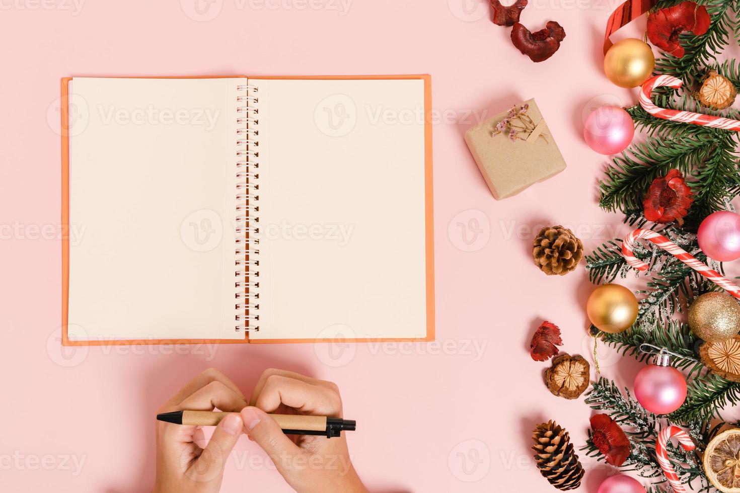 Minimal creative flat lay of winter christmas traditional composition and new year holiday season. Top view open mockup black notebook for text on pink background. Mock up and copy space photography. photo