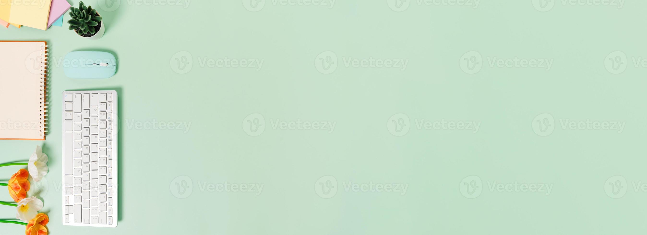 Creative flat lay photo of workspace desk. Top view office desk with keyboard, mouse and open mockup black notebook on pastel green color background. Top view mock up with copy space photography.