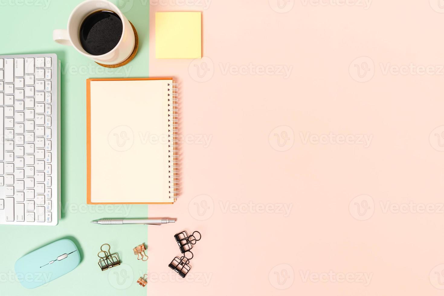 Foto creativa plana del escritorio del espacio de trabajo. escritorio de oficina de vista superior con teclado, mouse y cuaderno negro de maqueta abierta sobre fondo de color rosa verde pastel. vista superior maqueta con fotografía de espacio de copia.