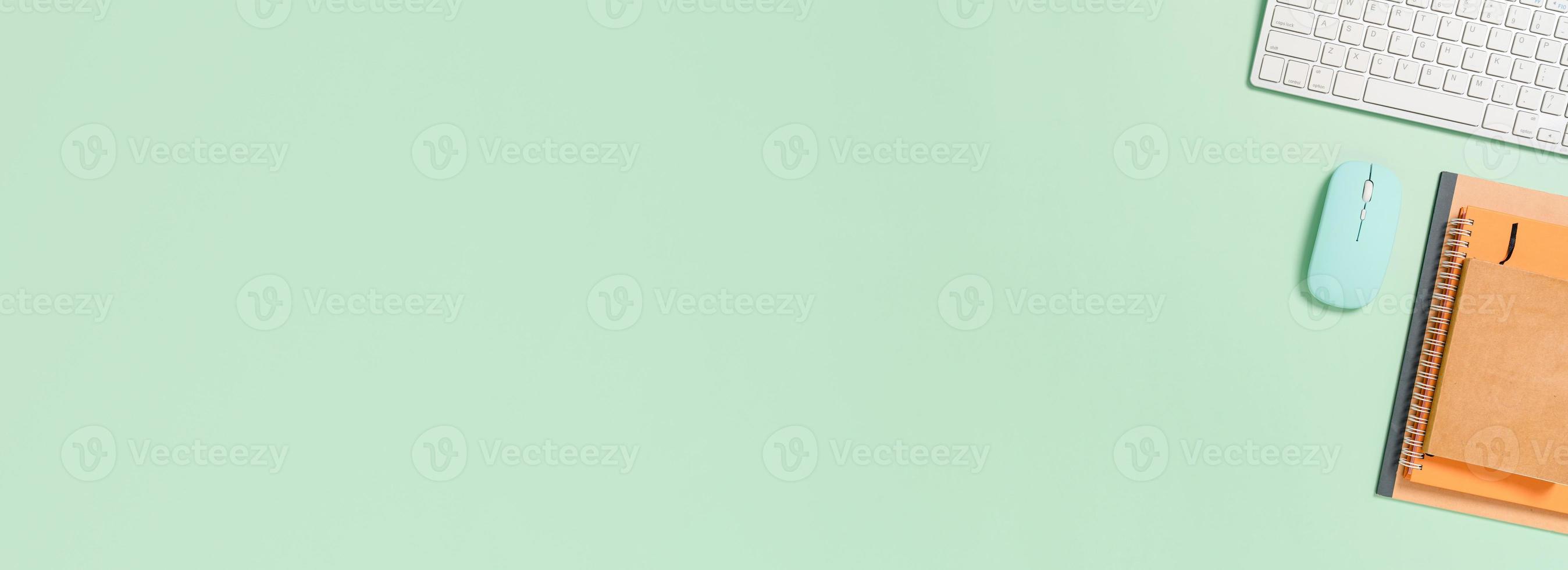 Creative flat lay photo of workspace desk. Top view office desk with keyboard, mouse and book on pastel green color background. Panoramic banner with copy space for text and Advertising area.