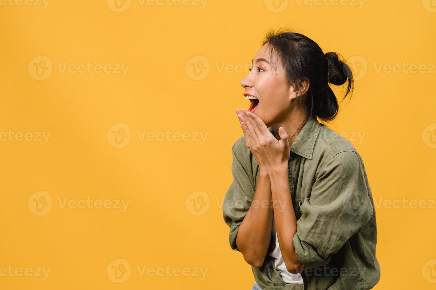 Young Asia lady feel happiness with positive expression, joyful surprise funky, dressed in casual cloth isolated on yellow background. Happy adorable glad woman rejoices success. Facial expression. photo