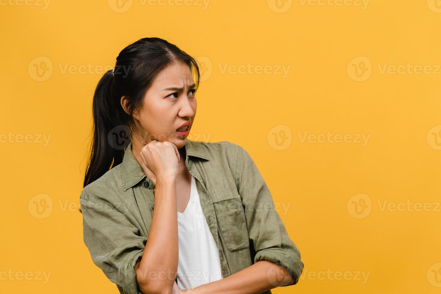 Retrato de joven asiática con expresión negativa, gritos emocionados, llorando emocionalmente enojado en ropa casual aislado sobre fondo amarillo con espacio de copia en blanco. concepto de expresión facial. foto