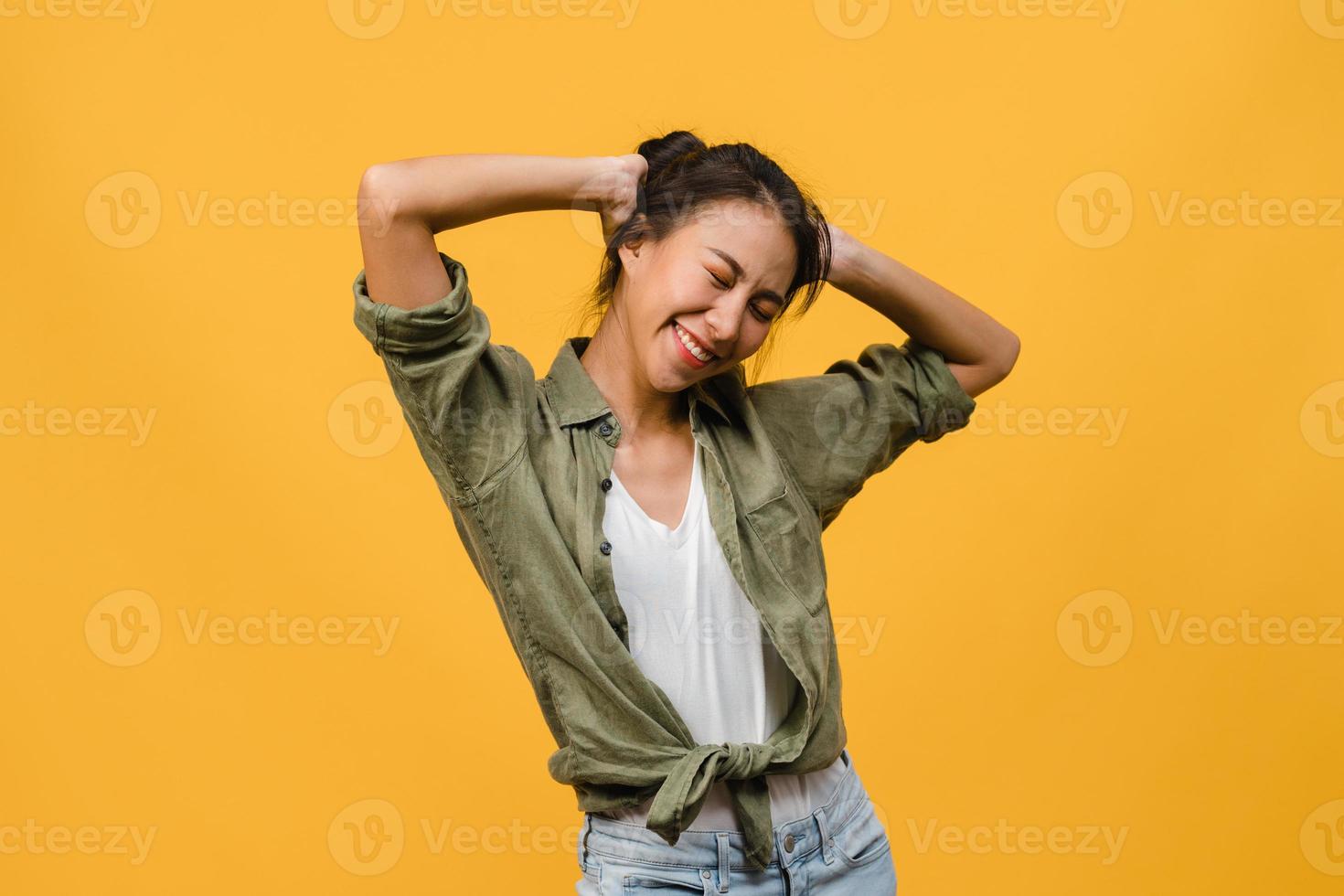 Portrait of young Asia lady with positive expression, smile broadly, dressed in casual clothing over yellow background. Happy adorable glad woman rejoices success. Facial expression concept. photo