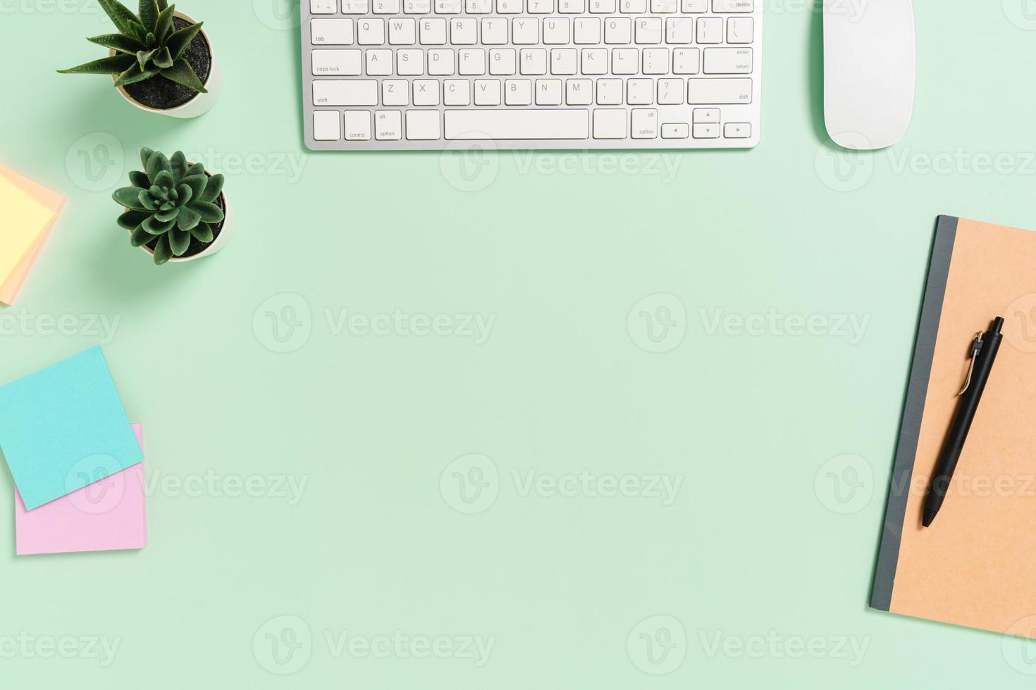 espacio de trabajo mínimo: foto creativa plana del escritorio del espacio de trabajo. escritorio de oficina de vista superior con teclado, mouse y libro sobre fondo de color verde pastel. vista superior con espacio de copia, fotografía plana.