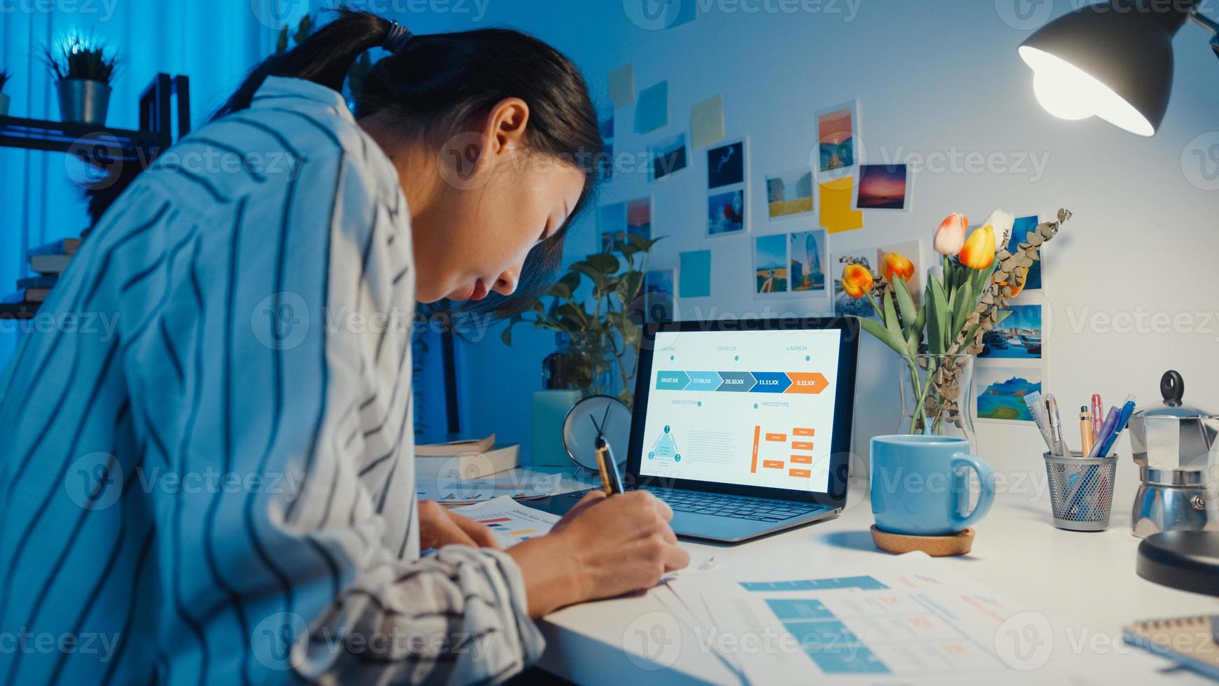 joven mujer de negocios de asia freelance centrarse en la computadora portátil escribir hoja de cálculo finanzas gráfico gráfico de cuenta plan de mercado en computadora portátil y tableta en la noche de la casa. chica estudiante aprende en línea, trabaja desde el concepto de hogar. foto