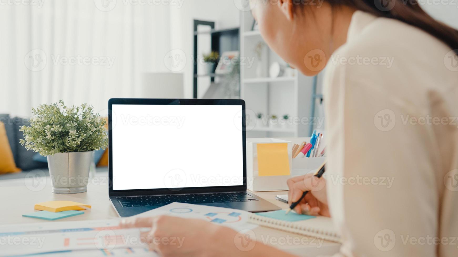 Young Asia businesswoman use smart phone with blank white screen mock up display for advertising text while smart working from home at living room. Chroma key technology, Marketing design concept. photo