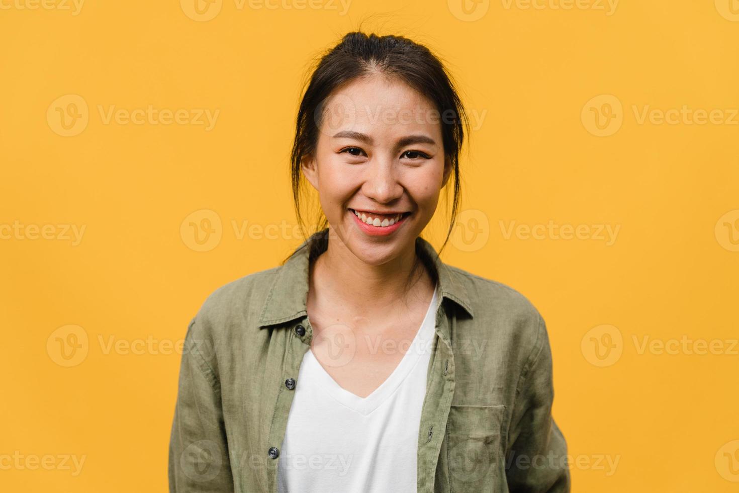 Young Asia lady with positive expression, smile broadly, dressed in casual clothing and looking at camera over yellow background. Happy adorable glad woman rejoices success. Facial expression concept. photo