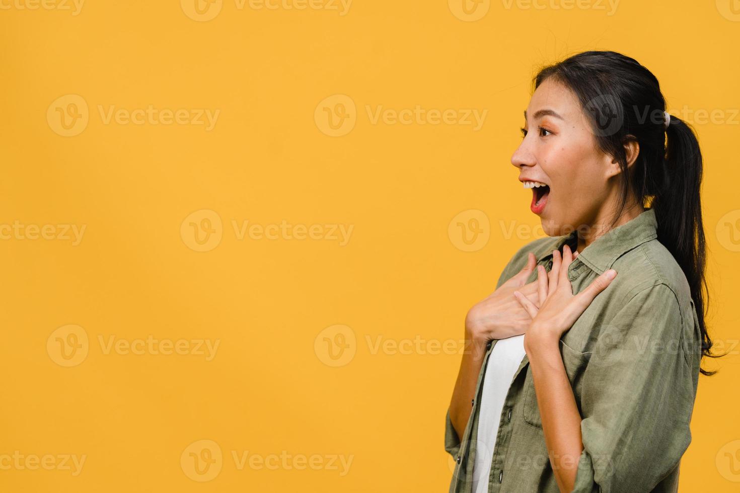 La joven dama de Asia siente felicidad con expresión positiva, alegre sorpresa funky, vestida con un paño casual aislado sobre fondo amarillo. feliz adorable mujer alegre se regocija con el éxito. expresión facial. foto