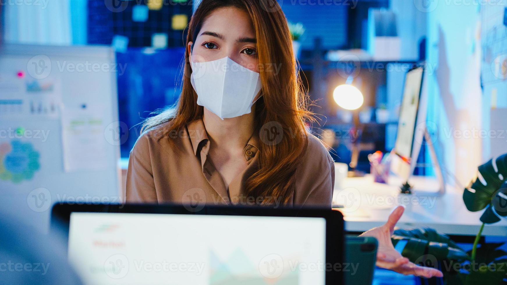Asia businesspeople using laptop presentation and communication meeting brainstorming ideas about new project colleagues working plan success strategy wear face mask back in new normal night office. photo