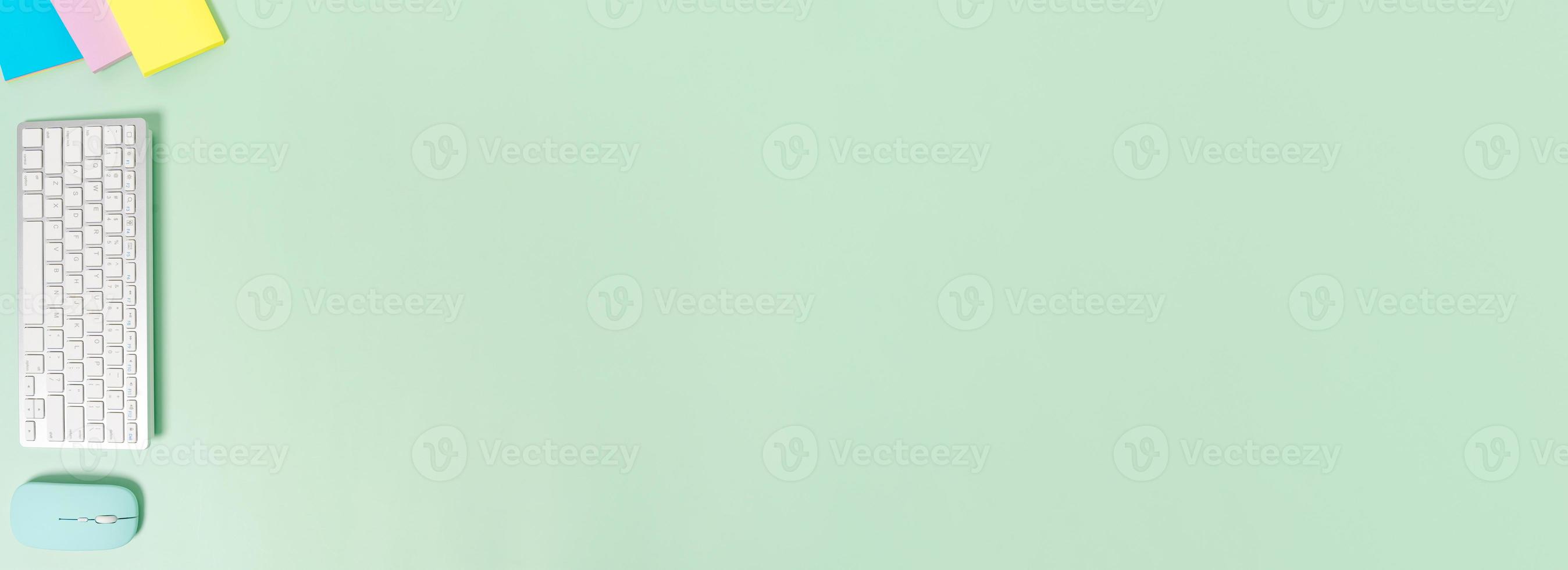 Creative flat lay photo of workspace desk. Top view office desk with keyboard and mouse on pastel green color background. Panoramic banner with copy space for text and Advertising area.