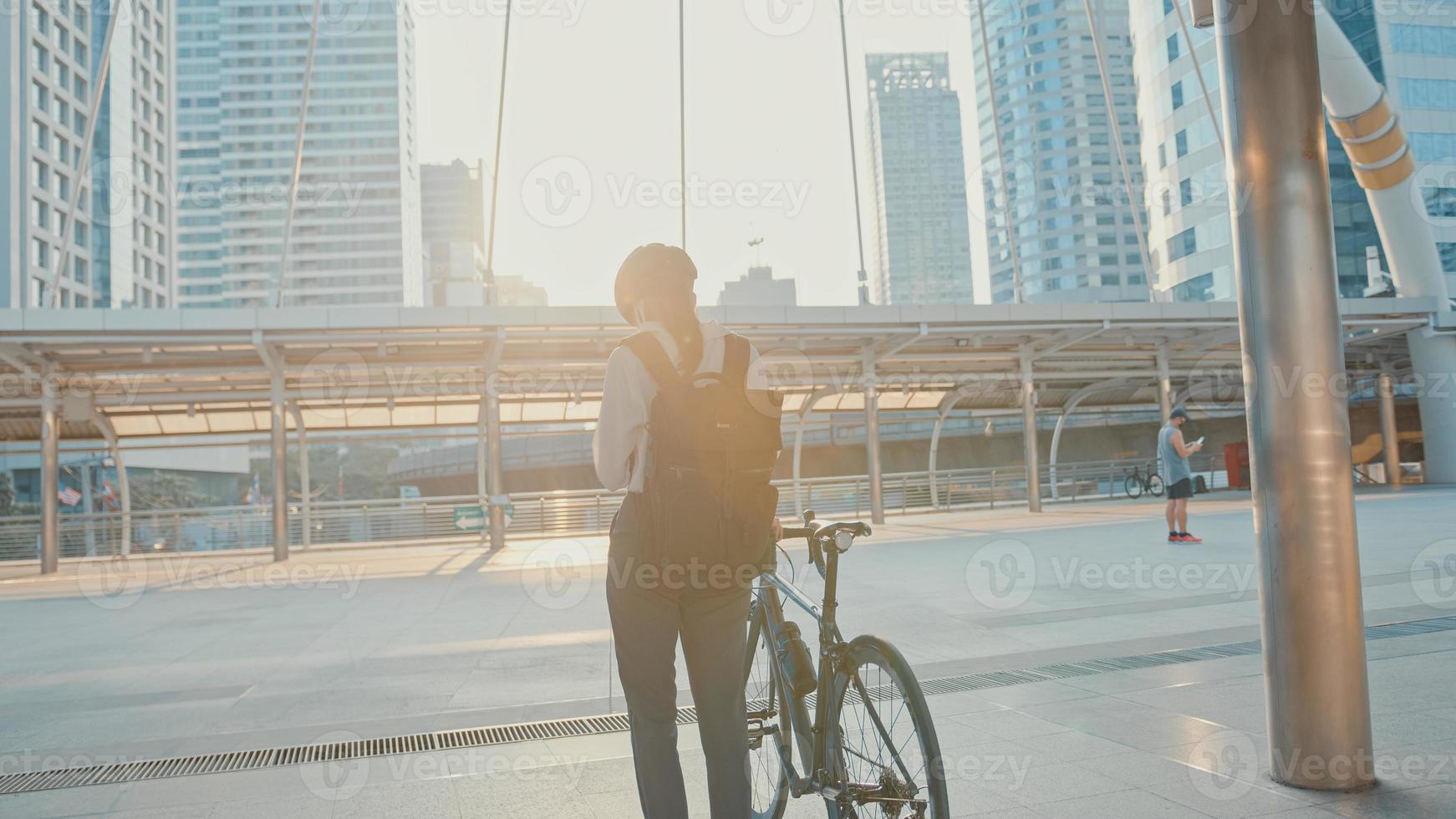 empresaria asiática con mochila usa máscara de protección antivirus contra coronavirus caminar en bicicleta en una calle de la ciudad ir a trabajar en la oficina. viaje diario al trabajo, viajero de negocios para el concepto covid-19. foto