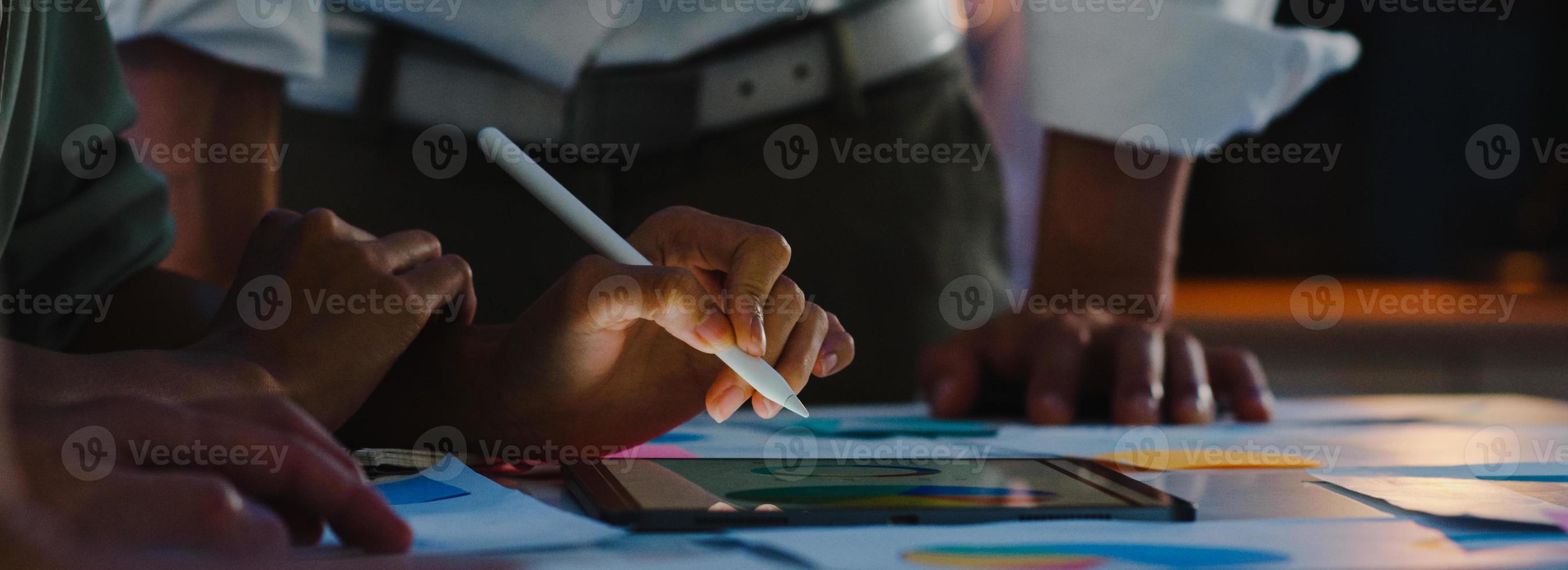 Asia businessmen and businesswomen meeting brainstorming ideas colleagues working together planning success strategy enjoy teamwork in night office. Panoramic banner background with copy space. photo