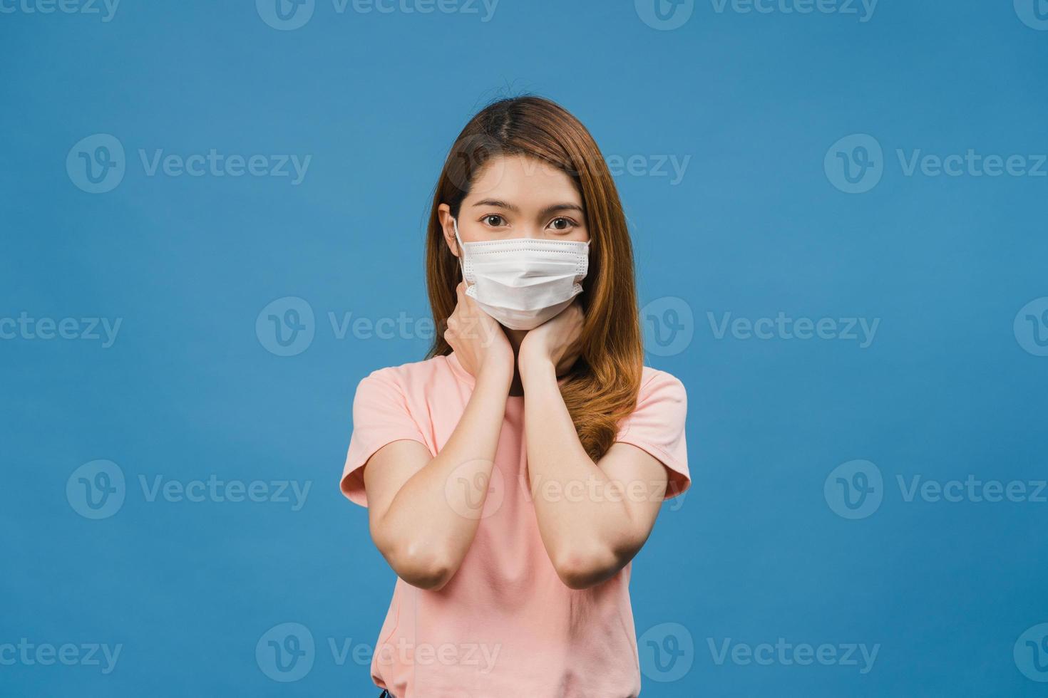 Young Asia girl wear medical face mask, tired of stress and tension, looks confidently at camera isolated on blue background. Self-isolation, social distancing, quarantine for corona virus prevention. photo