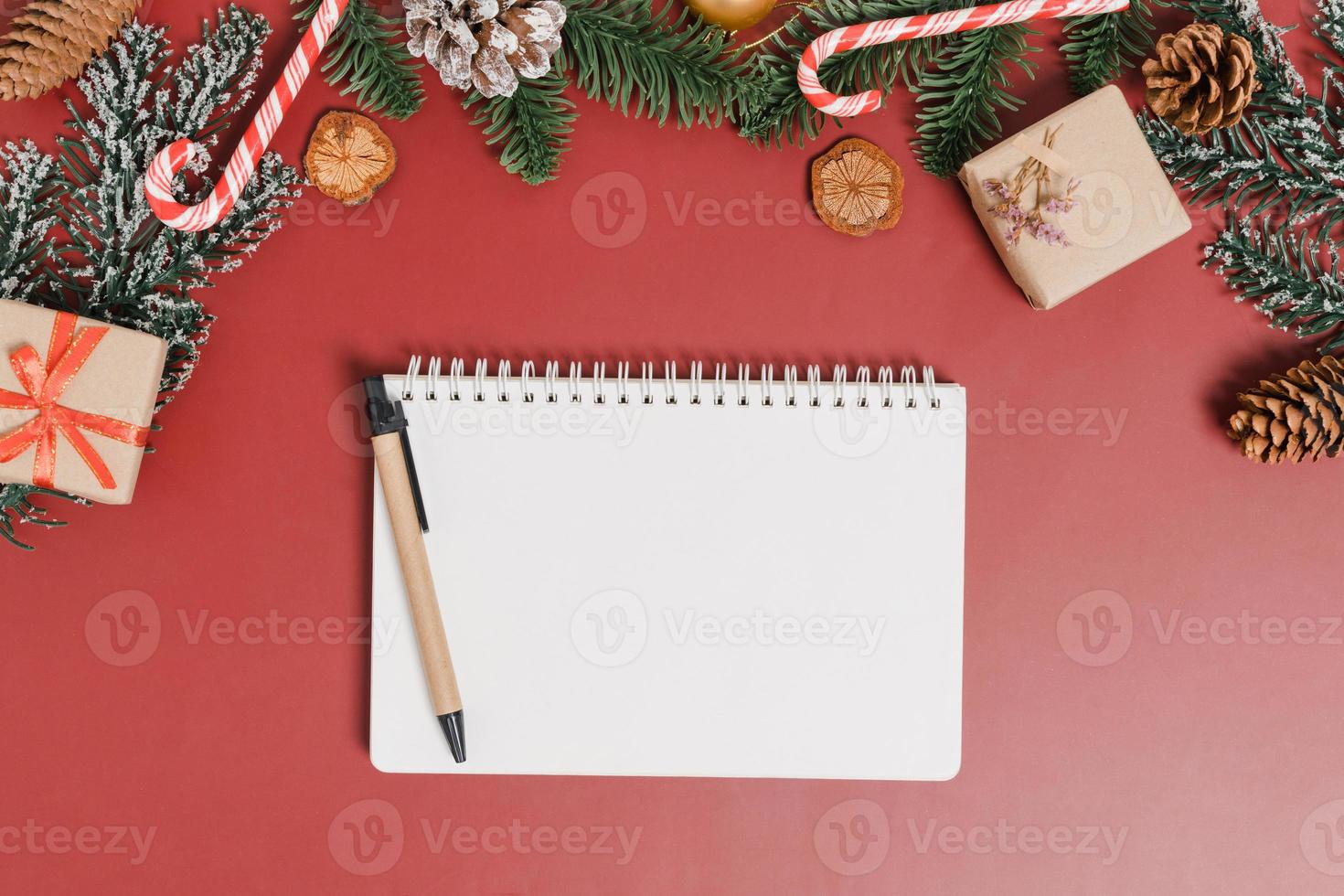 Minimal creative flat lay of winter christmas traditional composition and new year holiday season. Top view open mockup black notebook for text on red background. Mock up and copy space photography. photo