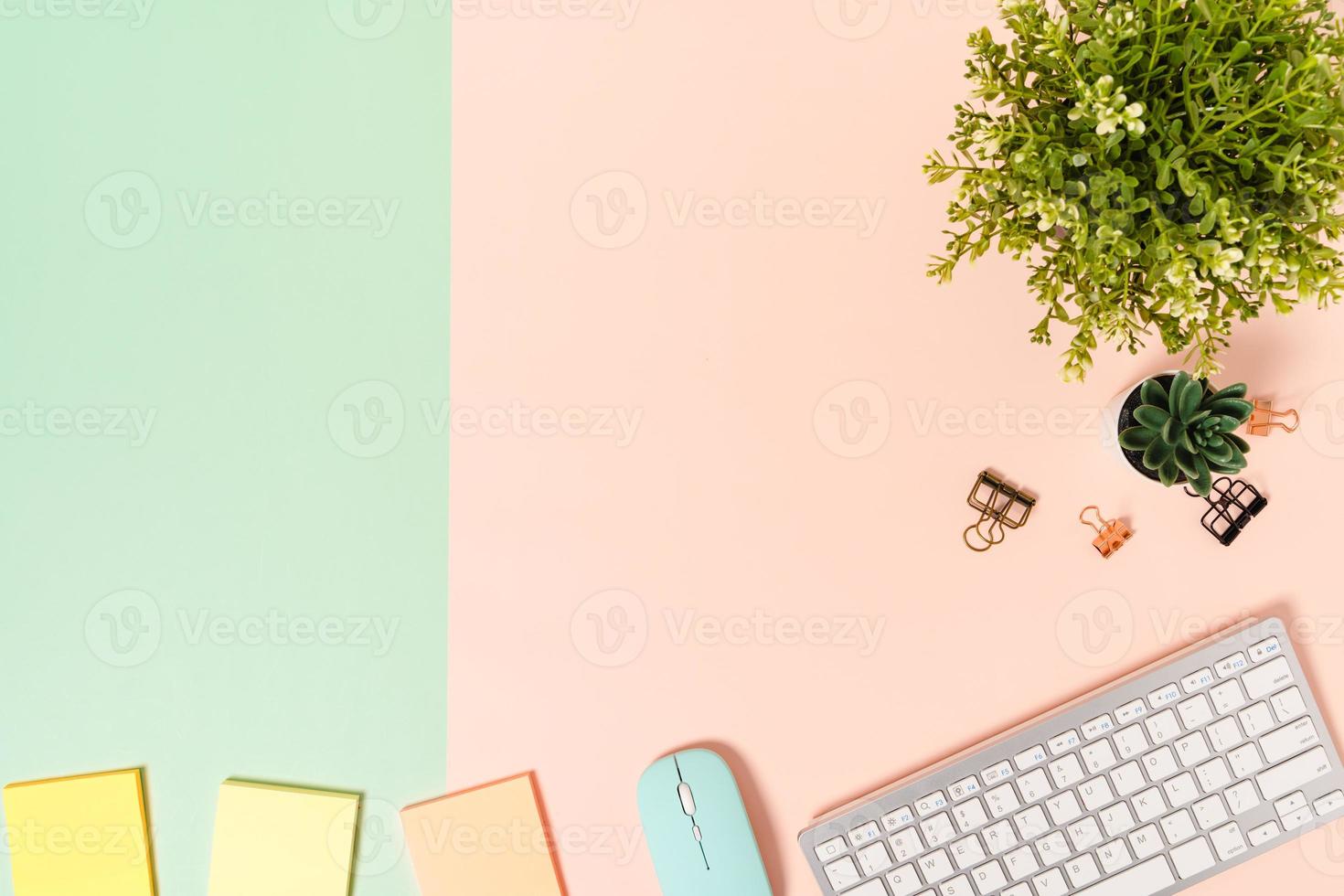 Minimal work space - Creative flat lay photo of workspace desk. Top view office desk with keyboard, mouse and adhesive note on pastel green pink color background. Top view with copy space photography.