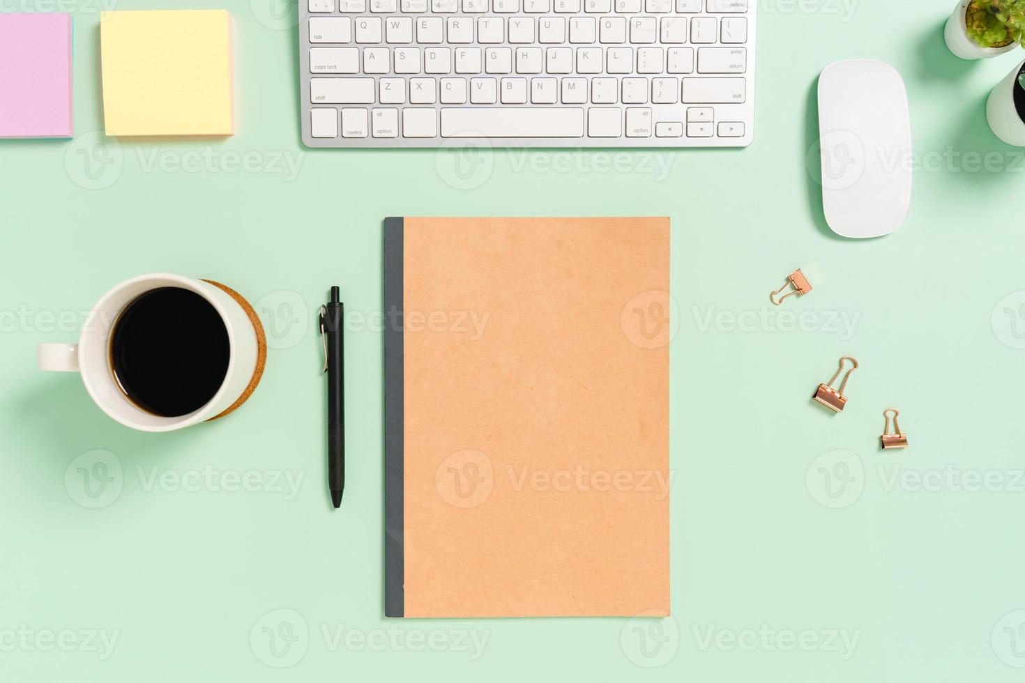 Creative flat lay photo of workspace desk. Top view office desk with keyboard, mouse and mockup black notebook on pastel green color background. Top view mock up with copy space photography.