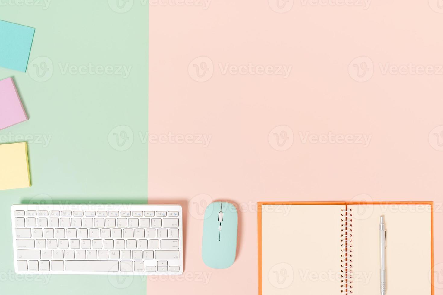 Creative flat lay photo of workspace desk. Top view office desk with keyboard, mouse and open mockup black notebook on pastel green pink color background. Top view mock up with copy space photography.