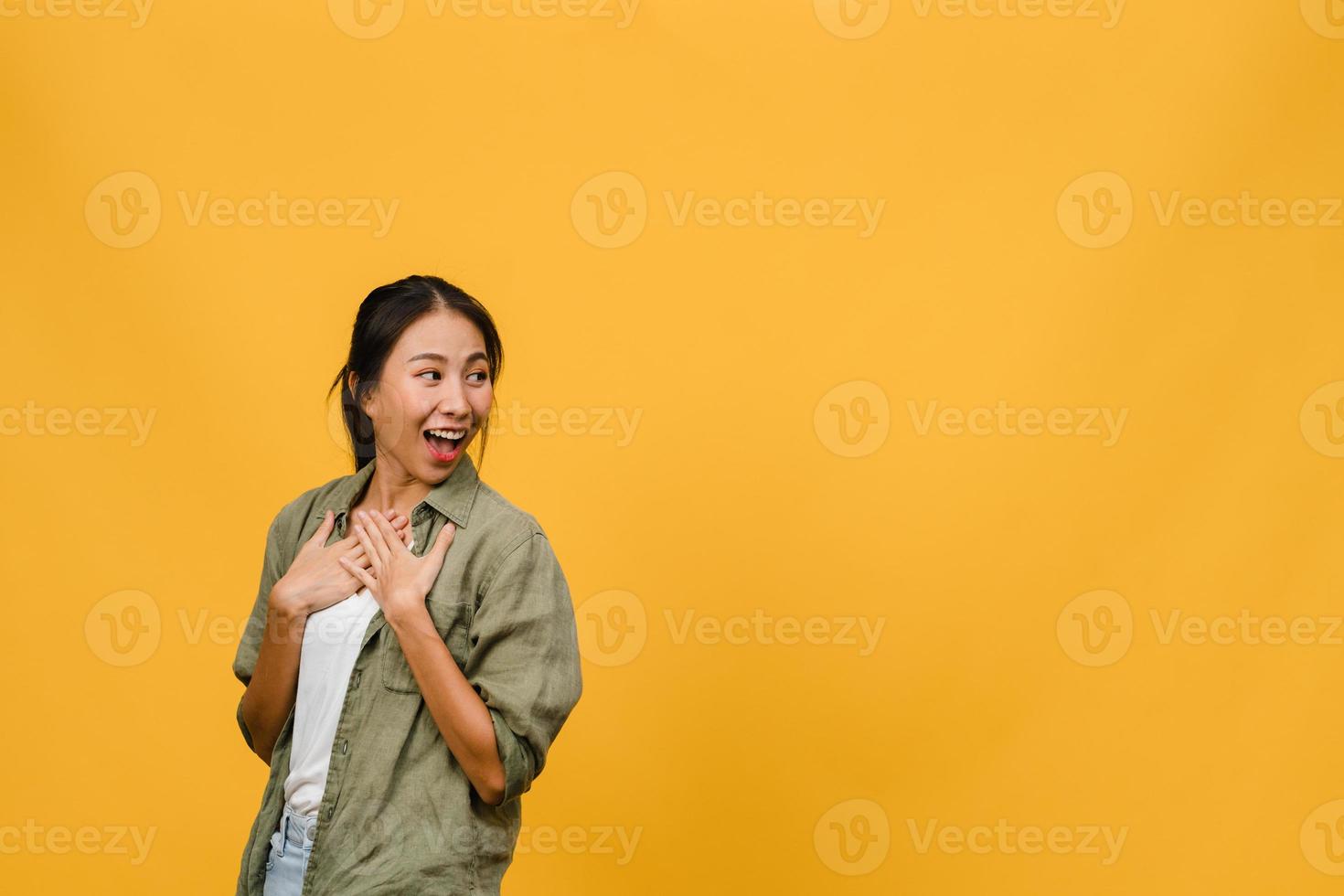 Portrait of young Asia lady with positive expression, smile broadly, dressed in casual clothing over yellow background. Happy adorable glad woman rejoices success. Facial expression concept. photo