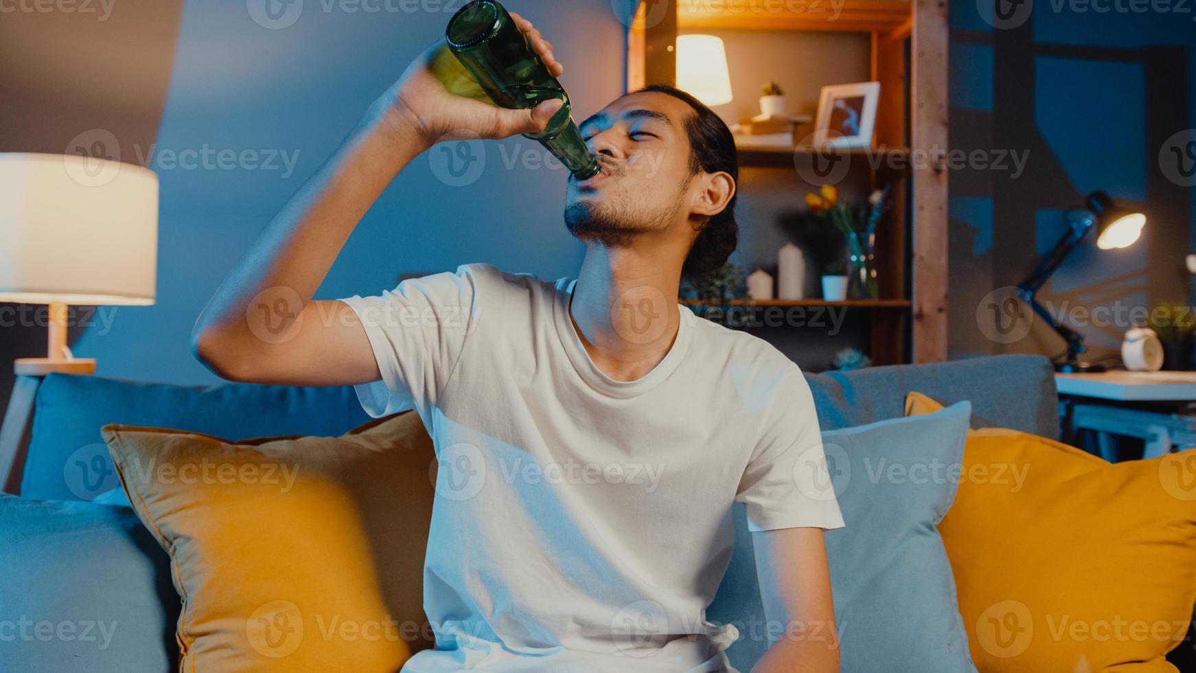 feliz joven asiático mirando a la cámara disfrutar de un evento de fiesta nocturna en línea con amigos brindis beber cerveza a través de videollamadas en línea en la sala de estar en casa, quedarse en casa cuarentena, concepto de distanciamiento social. foto