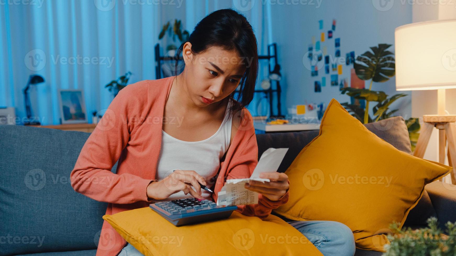 Asian lady feel stress and worried with bill and invoice credit card calculating loan on sofa at home. Home loan stress, Get loan no job,  Coronavirus hardship loans, Can't make loan payment concept. photo
