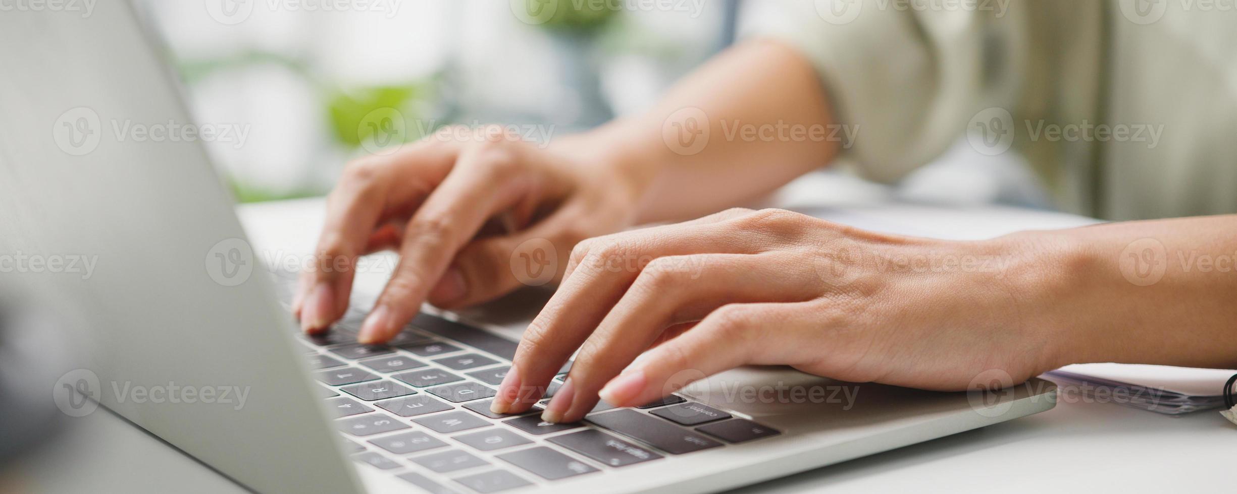 Freelance Asia businesswoman casual wear using laptop working in living room at home. Remotely, social distance, quarantine for corona virus prevention. Panoramic banner background with copy space. photo