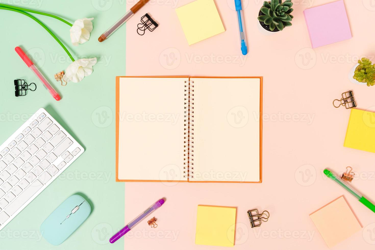 Creative flat lay photo of workspace desk. Top view office desk with keyboard, mouse and open mockup black notebook on pastel green pink color background. Top view mock up with copy space photography.
