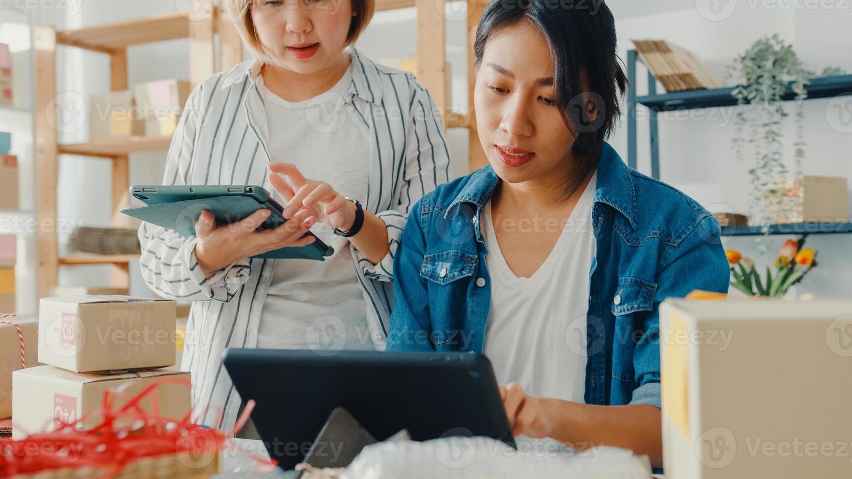 Reunión de jóvenes empresarias de Asia comprobar la orden de compra del producto en stock y guardarlo en el trabajo de la tableta en la oficina en casa. propietario de una pequeña empresa, entrega de mercado en línea, concepto independiente de estilo de vida. foto