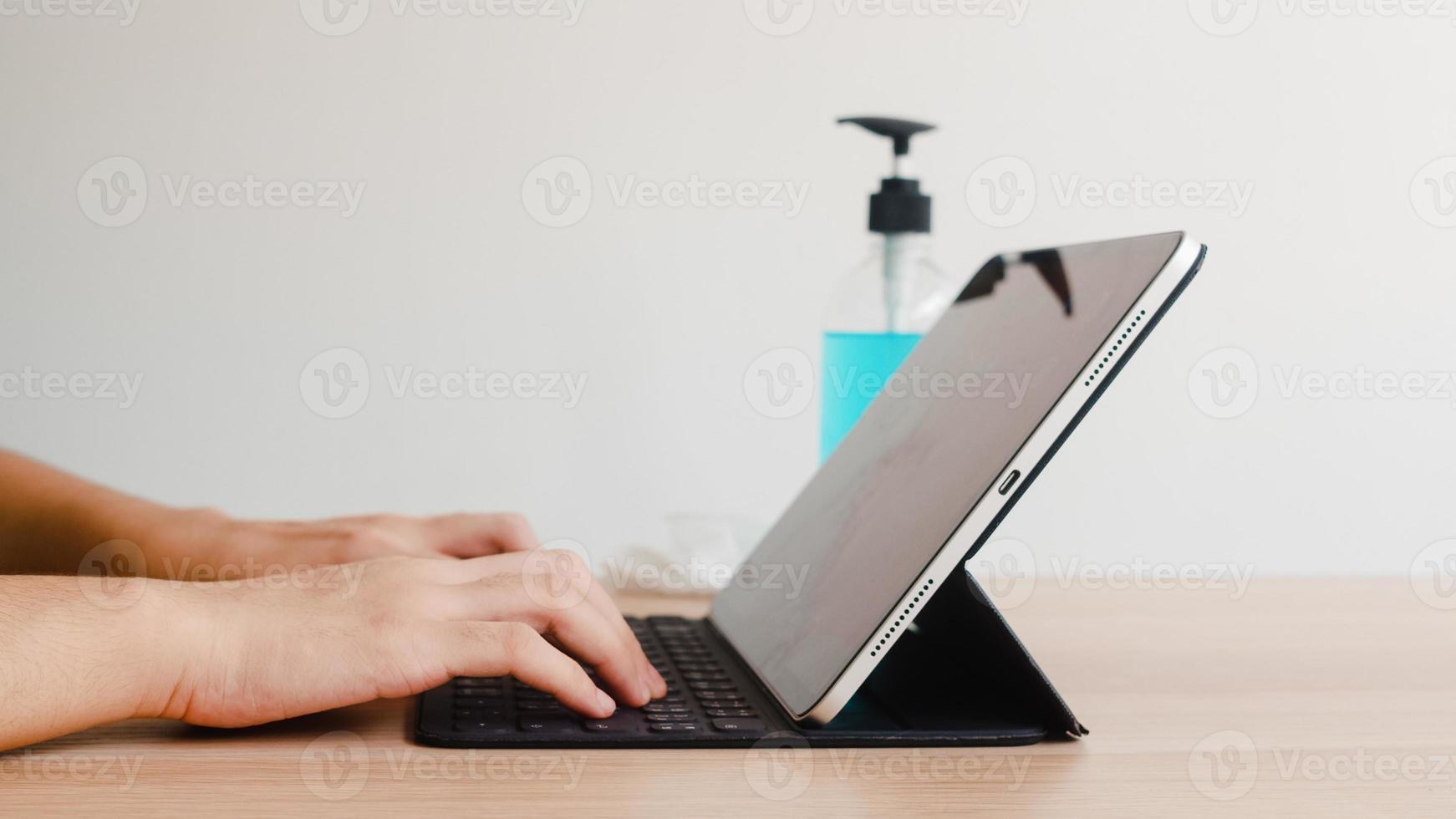 Asian woman using alcohol gel sanitizer wash hand before using tablet for protect coronavirus. Female push alcohol to clean for hygiene when social distancing stay at home and self quarantine time. photo