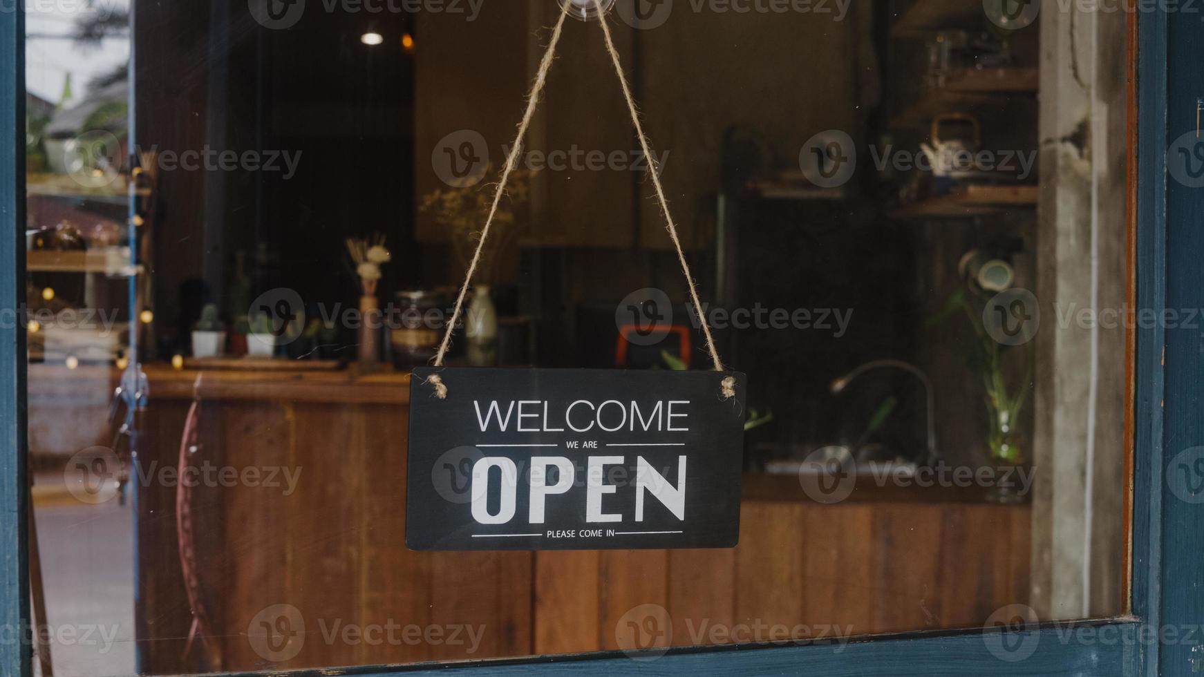 Welcome we're open vintage black and white retro sign on a coffee glass door cafe after coronavirus lockdown quarantine. Owner small business, food and drink, business reopen again concept. photo