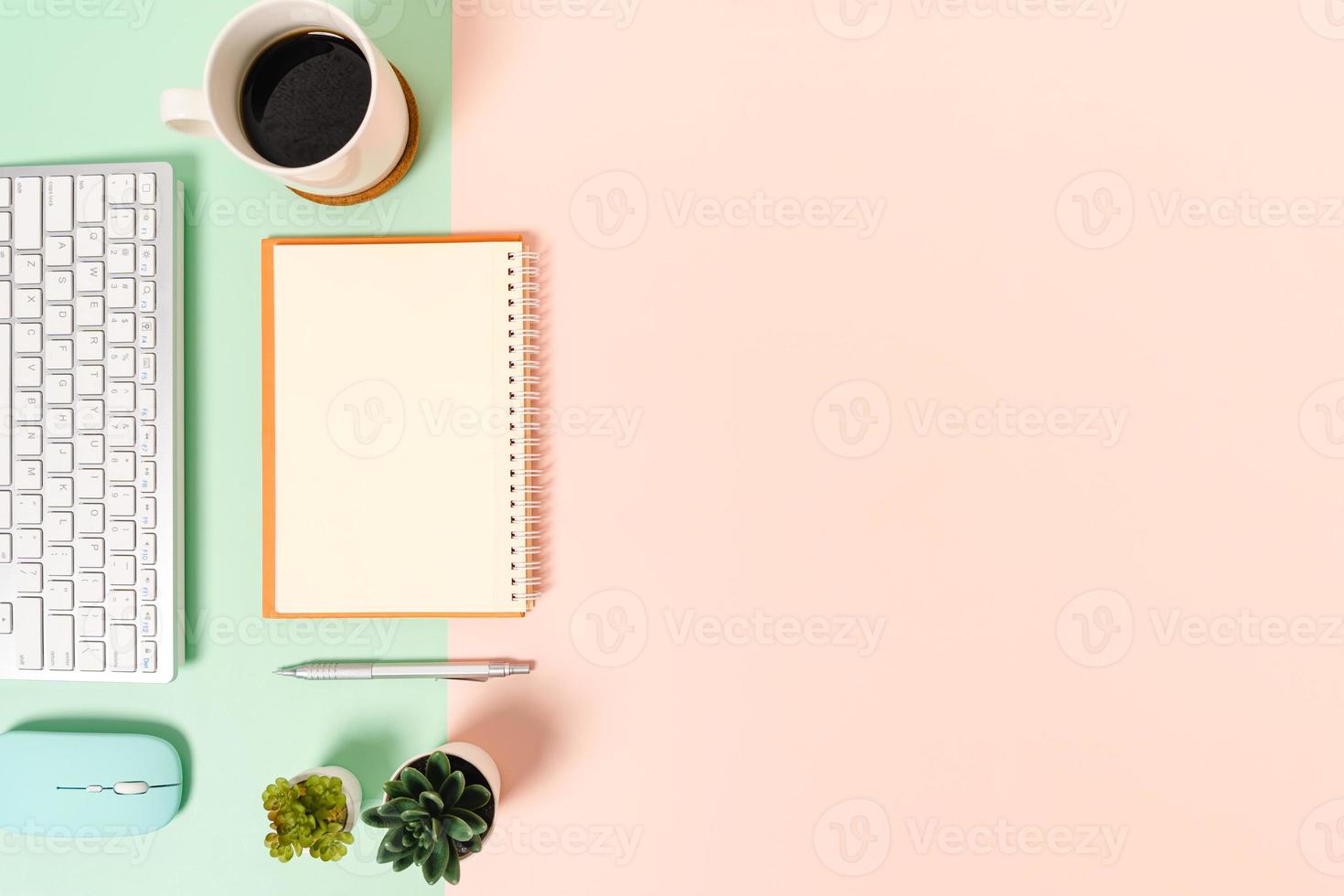 Foto creativa plana del escritorio del espacio de trabajo. escritorio de oficina de vista superior con teclado, mouse y cuaderno negro de maqueta abierta sobre fondo de color rosa verde pastel. vista superior maqueta con fotografía de espacio de copia.