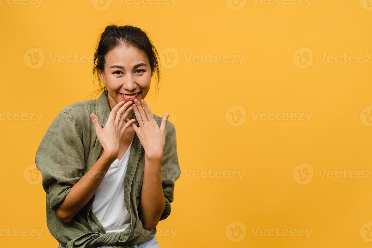Young Asia lady with positive expression, smile broadly, dressed in casual clothing and looking at camera over yellow background. Happy adorable glad woman rejoices success. Facial expression concept. photo