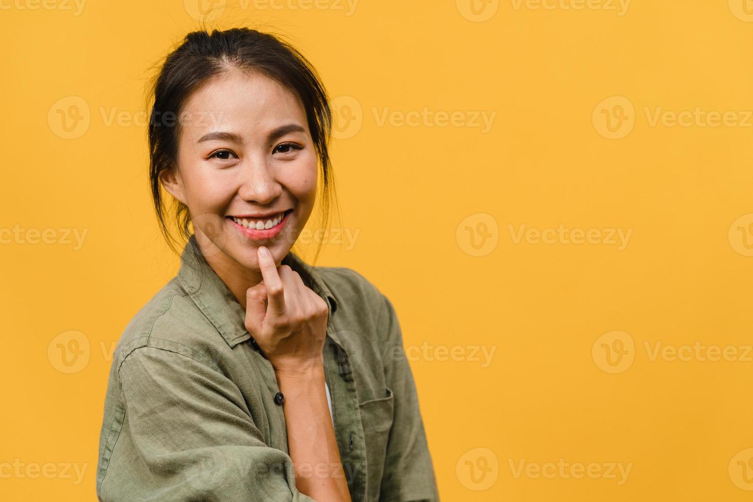 Young Asia lady with positive expression, smile broadly, dressed in casual clothing and looking at camera over yellow background. Happy adorable glad woman rejoices success. Facial expression concept. photo