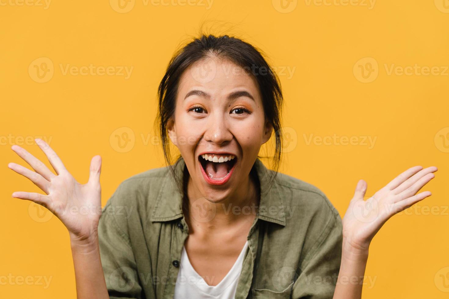 La joven asiática siente felicidad con expresión positiva, alegre sorpresa funky, vestida con ropa informal y mirando a cámara aislada sobre fondo amarillo. feliz adorable mujer alegre se regocija con el éxito. foto