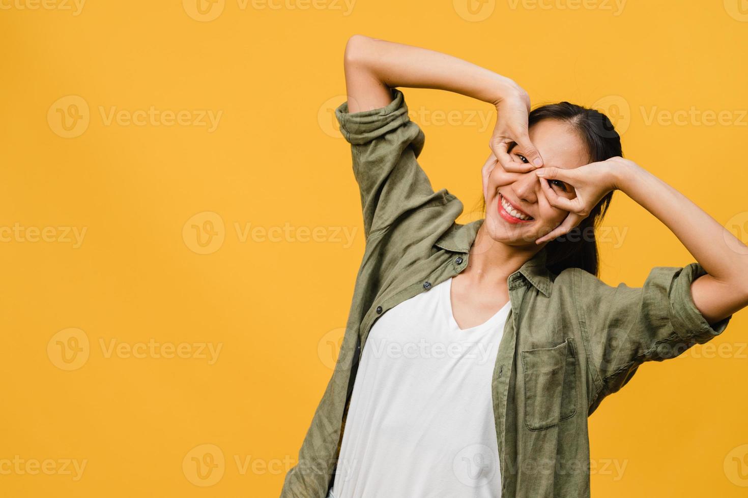 Jovencita asiática con expresión positiva, sonrisa amplia, vestida con ropa casual y mirando a cámara sobre fondo amarillo. feliz adorable mujer alegre se regocija con el éxito. concepto de expresión facial. foto