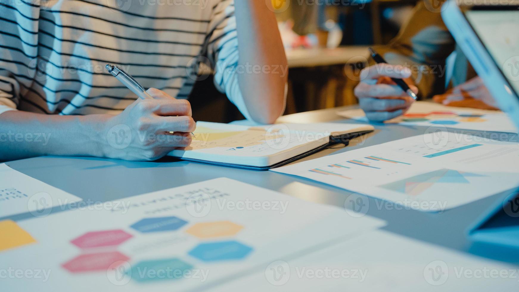 Asia businesspeople stand behind transparent glass wall listen manager pointing progress work and brainstorm meeting and worker post sticky note in office night. Business inspiration, share ideas. photo