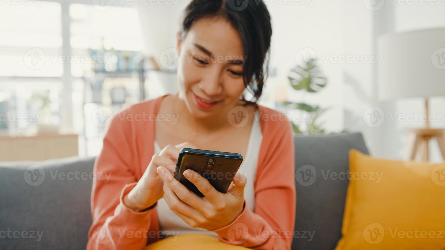 Beautiful lady using smartphone chat with couple sitting on sofa in living room at home in morning. Stay at home, Quarantine for covid, Nomophobia, Online shopping, Social network addiction concept. photo