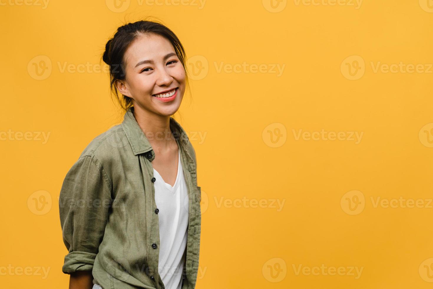 Jovencita asiática con expresión positiva, sonrisa amplia, vestida con ropa casual y mirando a cámara sobre fondo amarillo. feliz adorable mujer alegre se regocija con el éxito. concepto de expresión facial. foto