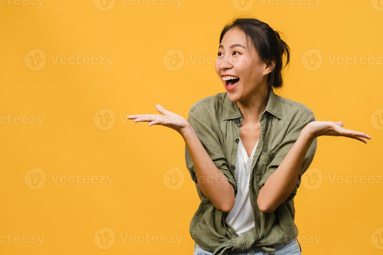 La joven dama de Asia siente felicidad con expresión positiva, alegre sorpresa funky, vestida con un paño casual aislado sobre fondo amarillo. feliz adorable mujer alegre se regocija con el éxito. expresión facial. foto