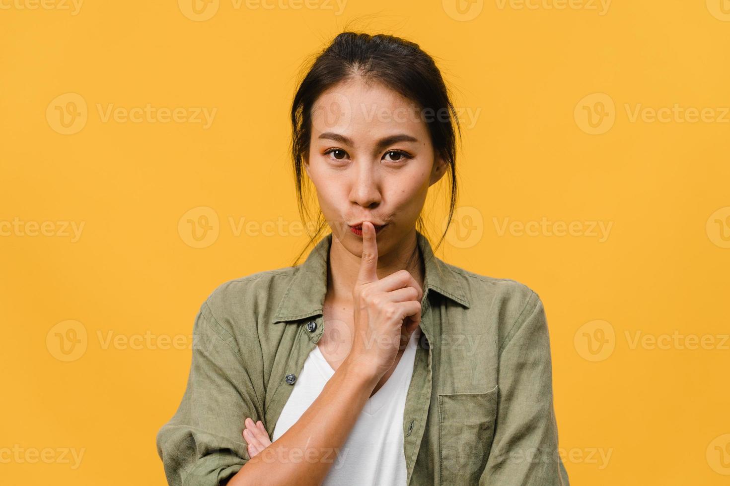 Portrait of young Asia lady with positive expression, thinks about coming holidays, dressed in casual clothing and looking at camera over yellow background. Happy adorable glad woman rejoices success. photo